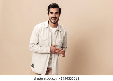 Stylish male smile model posing on a beige background in a white t-shirt looking at the camera, fashionable clothing style, copy space, space for text - Powered by Shutterstock