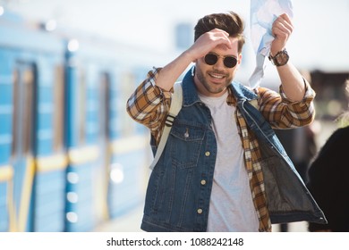 stylish male traveler in sunglasses holding map in hand at outdoor subway station  - Shutterstock ID 1088242148