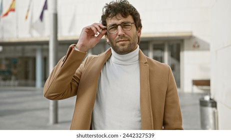 A stylish man adjusting glasses on an urban city street exudes confidence and fashion. - Powered by Shutterstock