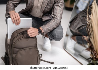 A stylish man apacking his backpack before leaving to work