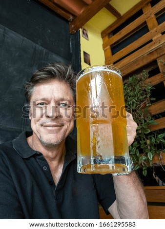 Stylish man drinking beer. Drinks, alcohol, leisure, people concept. Handsome man has mug of beer. Oktoberfest. Selective focus on the glass. 