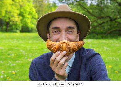 Stylish Man Eating A Croissant Outdoors