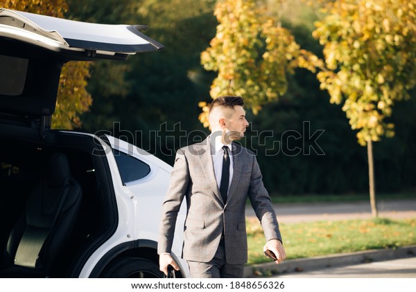 Stylish man getting out of car, personal\
chauffeur bringing businessman. Business man with briefcase get out\
from auto and walking to office\
building.