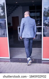 Stylish Man In Gray Jacket Walking Through Entrance Door Of Vehicle Repair Shop