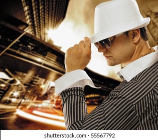 Stylish man in a hat in front of night city