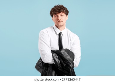Stylish man on a solid blue background, feeling confident and successful in a white shirt, black tie, and leather jacket