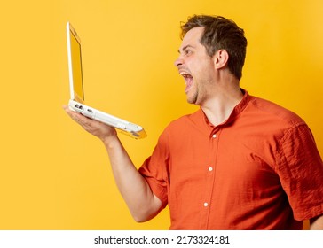 Stylish Man In Orange Shirt With Laptop Computer On Yellow Background