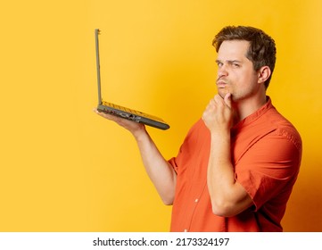 Stylish Man In Orange Shirt With Laptop Computer On Yellow Background