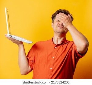 Stylish Man In Orange Shirt With Laptop Computer On Yellow Background