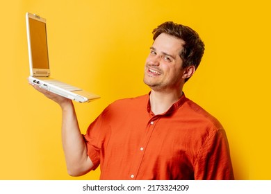 Stylish Man In Orange Shirt With Laptop Computer On Yellow Background