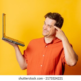 Stylish Man In Orange Shirt With Laptop Computer On Yellow Background