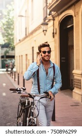 Stylish Man Pushing A Bicycle While Talking On The Phone