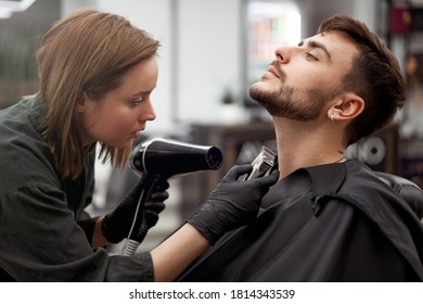 Stylish man sitting barber shop Hairstylist Hairdresser Woman blow dry his hair Portrait handsome happy young bearded caucasian guy getting trendy haircut Attractive barber serving client  - Powered by Shutterstock