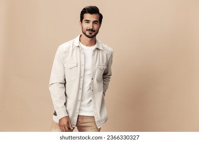 Stylish man smile on a beige background in a white t-shirt and business jacket, flying clothes hero, fashionable clothing style, copy space, space for text - Powered by Shutterstock