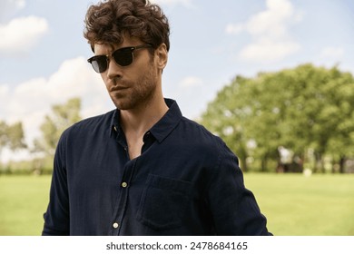 A stylish man in sunglasses stands confidently in a vast field, soaking in the tranquility around him. - Powered by Shutterstock