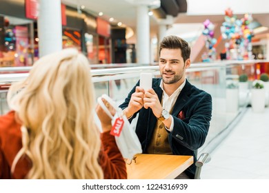 stylish man taking photo of girlfriend holding bag with sale tag - Shutterstock ID 1224316939
