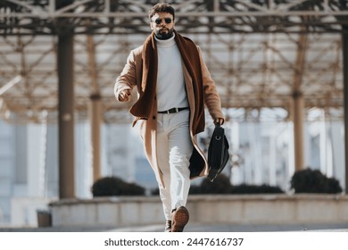 Stylish man walking in winter attire with confidence in urban setting. - Powered by Shutterstock