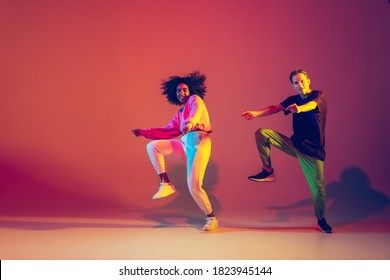 Hombre y mujer elegantes bailando hip-hop con ropa brillante de fondo verde en la sala de baile a la luz de neón. Cultura juvenil, hip-hop, movimiento, estilo y moda, acción. Retrato de moda.