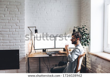 stylish man working with a computer on two monitors, designer or professional visualizer working on a project at home