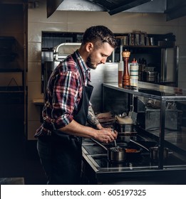 Stylish Master Chief Male With Tattoo On His Arm Grilling A Beef In A Kitchen.