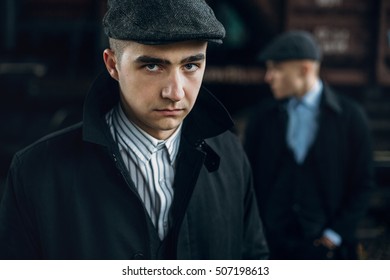 stylish men portrait in retro clothes posing on background of railway. england in 1920s theme. old fashionable look of brutal confident man