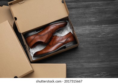 Stylish men's shoes and cardboard boxes on wooden floor, flat lay. Space for text