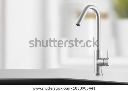 Stylish metallic crane at the kitchen.Shiny faucet at the kitchen.Metal crane in close-up photo.Modern furniture. Silver sink as kitchen equipment. Macro photo with high quality. Metallic faucet.