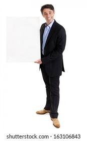 Stylish Middle Aged Businessman Or Salesman With A Cheesy Friendly Grin Standing Holding A Blank White Board For Your Text Or Advertisement, Isolated On White