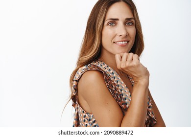 Stylish Middle Aged Female Model With Perfect Skin, Beautiful Eyes And Natural Makeup, Smiling Tenderly At Camera, Standing In Dress Over White Background