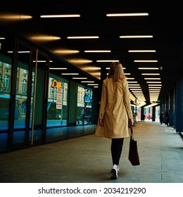 Stylish Millenial Woman In Coat Walks At City Street With Bag, Back View