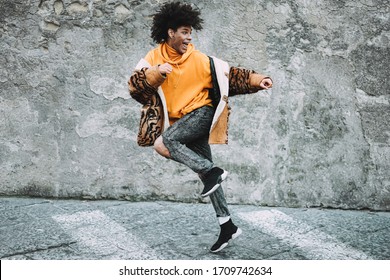 Stylish millennial guy dancing around city street outdoor - Young man having fun outside wearing trendy clothes - Z generation and fashion concept - Focus on his face