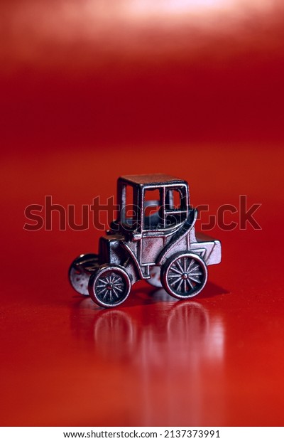 Stylish miniature car model, on a red background.\
A toy made of metal, covered with chrome, a miniature car model,\
silver color.
