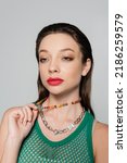stylish model with red lips pulling beads necklace isolated on grey