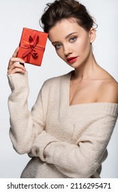 Stylish model in warm sweater holding red present isolated on white