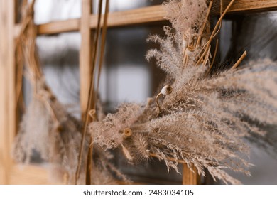 Stylish modern autumn wreath on wooden doors close up. Fall decor of farm house entrance. Rustic wreath with dried grass, herbs and ribbon. - Powered by Shutterstock