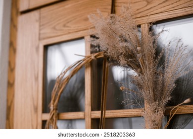 Stylish modern autumn wreath on wooden doors. Fall decor of farm house entrance. Rustic wreath with dried grass, herbs and ribbon. Thanksgiving and Halloween - Powered by Shutterstock