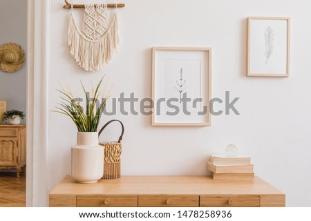 Stylish and modern boho interior of living room with mock up photo frames, flowers in vase, wooden desk, beige macrame and elegant accessories. Design home decor. Bohemian concept. Mockup ready to use
