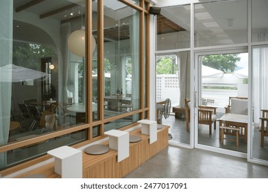 A stylish modern cafe interior featuring large glass windows, wooden furniture, and a minimalist decor, creating a bright and inviting atmosphere. - Powered by Shutterstock