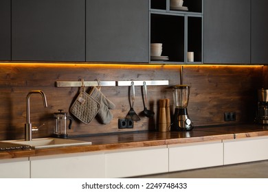 Stylish modern kitchen with a wooden apron. Workplace lighting. Black and white cabinets - Powered by Shutterstock