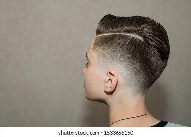 Stylish modern retro haircut side part with mid fade with parting of school boy guy in a barbershop on a brown background - Shutterstock ID 1533656150