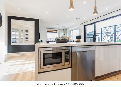 A stylish modular kitchen counter with a pre-installed oven and dishwasher and a showpiece at the counter with stylish lights hanging over.