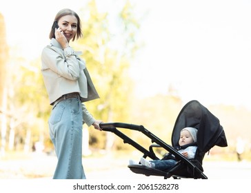 Stylish Mom With Stroller Talking On The Phone In Autumn Park