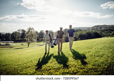 Stylish multicultural friends spending time together while playing golf on golf course - Powered by Shutterstock