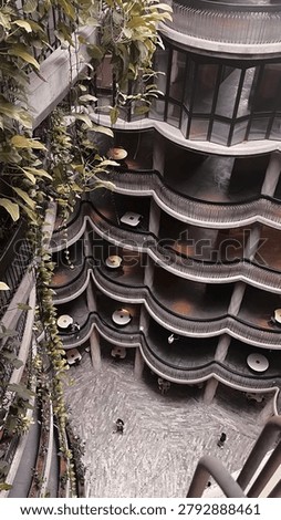A stylish multi-level atrium featuring flowing curved balconies, lush hanging plants, and modern minimalist architecture, creating an elegant and serene indoor atmosphere