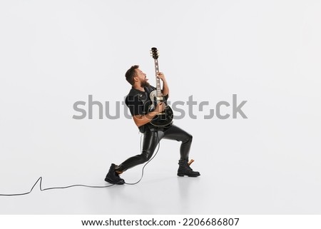 Stylish musician wearing retro style clothes playing guitar like rockstar isolated on white background. Vintage fashion, music, art, emotions, music festival concept. Copy space for ad