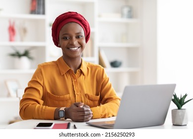 Stylish Muslim African American Woman In Casual Outfit Sitting At Worktable, Working On Laptop, Smiling At Camera, Posing Alone At Cozy Office, Copy Space. Millennials Business Concept