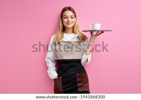 Stylish nice woman waitress in apron, offering cup of delicious tasty coffee
