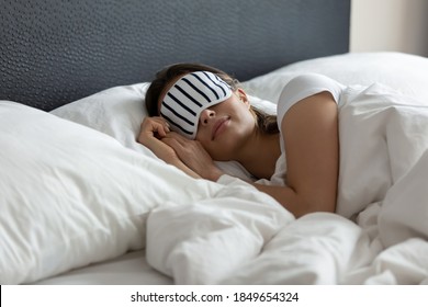 Stylish Nightwear. Comfy Sleeping Mask Helping Young Woman Tourist Traveler Enjoy Good Healthy Night Sleep At New Place In Hotel Suite Room, Millennial Woman Napping At Wide King Size Bed In Eye Mask