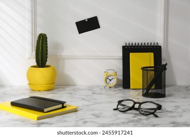 Stylish office workplace. Decor elements, cactus, glasses and stationery on marble table near white wall