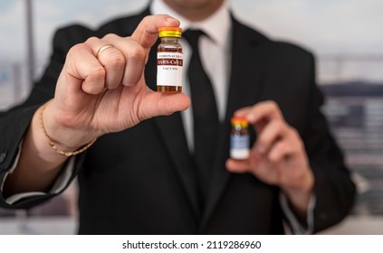 A Stylish Older Man In A Suit Carries The Vaccine In A Jar And Dollars For It. Vaccination Concept For Big Money